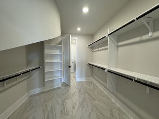 A spacious walk-in closet with elegant shelving, sleek rails, and marble-patterned tiles for a luxurious touch.