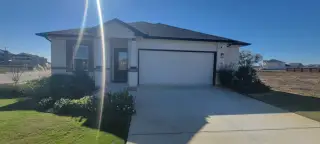 Street view A modern single-story home with a pristine lawn in Mesa Vista by CastleRock Communities (Von Ormy, TX).