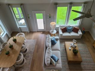 Model Home A cozy living area with plush sofas, a wooden coffee table, and large windows overlooking a green lawn, paired with a chic dining set.
