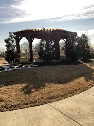 Community Amenities A scenic pergola area surrounded by lush greenery, offering a serene retreat within the community.