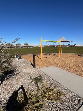 A vibrant playground with swings and shade in Sentiero at Windrose by David Weekley Homes (Waddell, AZ).