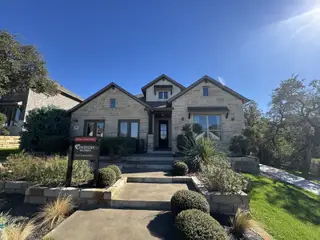 A charming stone home with manicured landscaping in 6 Creeks by Coventry Homes (Kyle, TX).