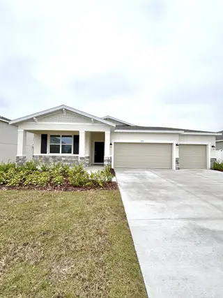 Street view A modern white home with stone accents and a spacious driveway in Brookshire by Stanley Martin Homes (Titusville, FL).