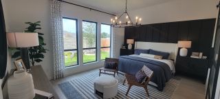 A cozy bedroom with a navy bed, stylish chandelier, patterned curtains, and large windows overlooking a serene garden.