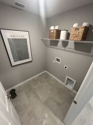 A sleek laundry room with modern gray tile flooring, storage baskets, and a stylish artwork on the wall.