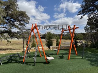 Community Amenities A vibrant playground with monkey bars set in lush greenery in Wolf Ranch by Pulte Homes (Georgetown, TX).