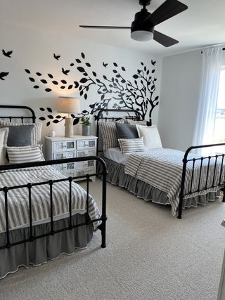 A charming bedroom with twin beds, artistic wall decals, and cozy lighting for a serene atmosphere.
