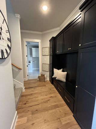 Model Home A cozy hallway with hardwood floors, built-in black cabinetry, and a decorative wall clock adding charm and functionality.