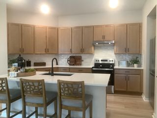 A modern kitchen featuring wooden cabinets, a sleek island with bar seating, and stainless appliances.