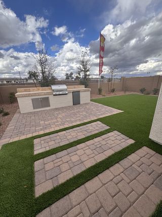A modern outdoor patio with built-in BBQ and sleek pavers in Seasons at Trevino II by Richmond American Homes (Glendale, AZ).