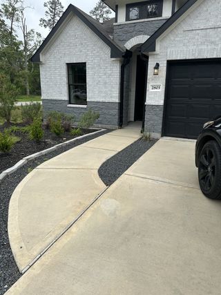 A chic gray brick home with black accents and a tidy walkway in Roman Forest by Stonefield Homes (New Caney, TX).