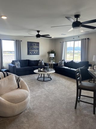 Model Home A modern living room with plush navy sofas, round table, and large windows providing a scenic view.