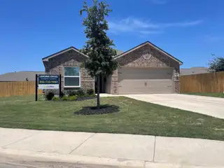Street view A charming brick home with manicured lawn in Preserve at Medina by LGI Homes (San Antonio, TX).