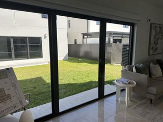 A bright living room with glossy tile flooring, sliding glass doors, and a view of a fenced backyard.