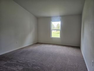 Model Home A spacious room with plush carpet and a single window letting in natural light.