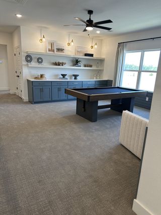 Model Home A stylish game room with a modern pool table, blue cabinetry, and sleek lighting features.