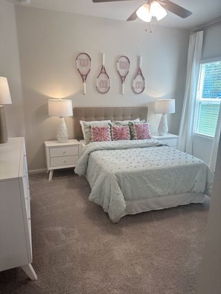 A cozy bedroom featuring a stylish bed with pastel bedding, decorative tennis rackets, and elegant bedside lamps.