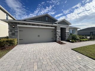 A modern stone-accented home with a spacious driveway in Reserve at Forest Lake I by KB Home (Lake Wales, FL).