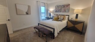 A cozy bedroom with modern decor, plush carpeting, stylish artwork, and elegant lamps creating a warm and inviting ambiance.