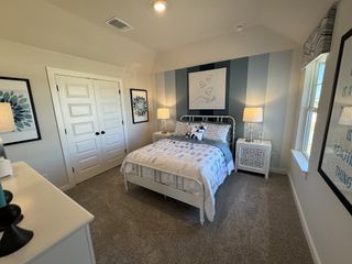 A cozy bedroom with striped walls, elegant artwork, soft carpeting, and a charming bed.