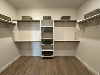 Spacious walk-in closet with wooden floors, white shelving, and organized baskets for stylish storage solutions.