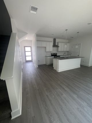 Model Home Expansive open living flows seamlessly into a modern kitchen, featuring sleek gray floors and crisp white cabinetry.