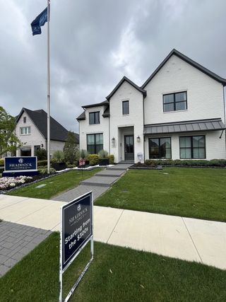 Street view A striking white brick home with a lush lawn in Devonshire by Shaddock Homes, Forney, TX, offering elegance and charm.