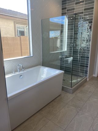 Model Home A modern bathroom with a freestanding tub, glass-enclosed shower with dark tile accents, and neutral tile flooring offers a luxurious spa-like feel.