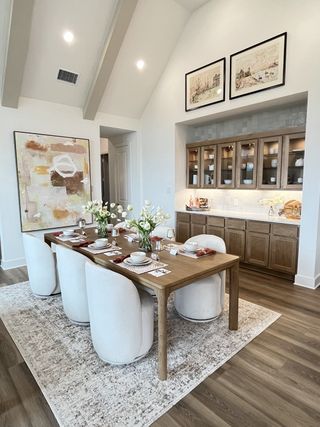 A chic dining area featuring a wooden table, plush chairs, and elegant artwork, complete with a stylish built-in cabinet.