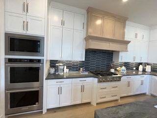 A modern kitchen with sleek white cabinetry, stainless steel appliances, and a stylish hexagonal tile backsplash.