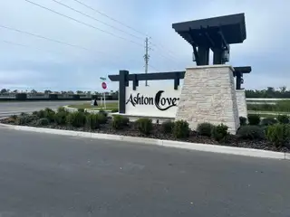 Street view Welcome to Ashton Cove by Ryan Homes, featuring elegant entry signage and lush landscaping in Winter Haven, FL.