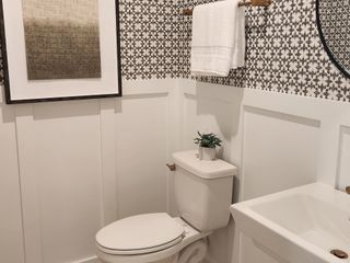 A chic bathroom with patterned wallpaper, a white vanity, and elegant wall art for a stylish touch.