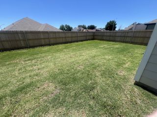 Spacious, fenced backyard with lush grass in Sycamore Landing by Legend Homes (Fort Worth, TX).