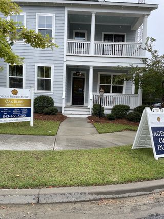 Street view A charming two-story home with classic columns and a welcoming porch in Oak Bluff by Dream Finders Homes (Charleston, SC).