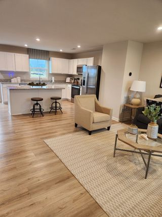 A modern open-plan living area with cozy seating, wood floors, and a sleek kitchen featuring stainless appliances.