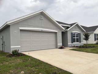 A modern gray home with blue shutters and tidy landscaping in Autumn Glen by D.R. Horton (Belleview, FL).