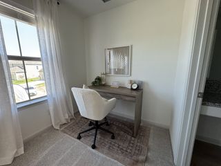 Model Home A cozy home office with a plush chair, wooden desk, and soft natural lighting.