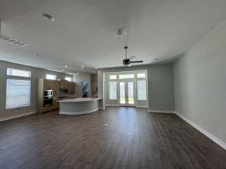 A spacious open-plan kitchen and living area with wood floors, large windows, and modern cabinetry.