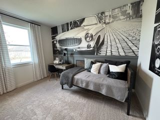 A chic bedroom featuring a sleek daybed, classic car mural, and cozy workspace by the window.