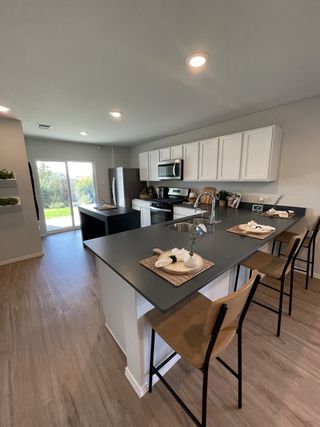 Modern kitchen featuring sleek black countertops, white cabinetry, and a spacious island with seating, opening to a bright outdoor view.