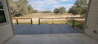 A spacious backyard deck overlooking serene open land and trees, perfect for relaxation and outdoor entertainment.