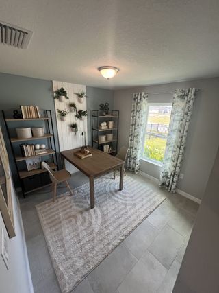 A cozy study with a modern desk, stylish bookshelves, and a large window with patterned curtains.
