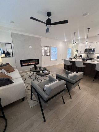 A modern living room with sleek decor, featuring a cozy fireplace, chic seating, and open kitchen with pendant lighting.