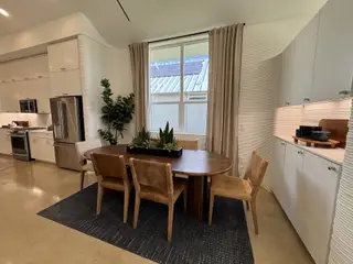 A modern dining area with a wooden table, leather chairs, and sleek cabinetry, complemented by plants and soft lighting.