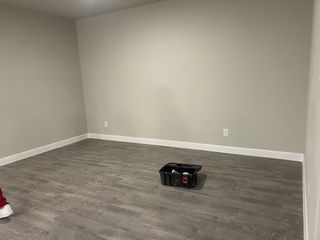 Model Home A spacious room with gray-toned wood flooring and neutral walls, perfect for personalized design and decor.