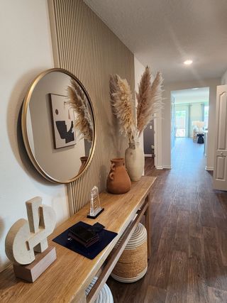 Model Home A welcoming entryway with wood flooring, textured wall paneling, and chic décor in Copes Landing by D.R. Horton (Jacksonville, FL).