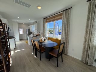 A bright kitchen-dining area with sleek white cabinets, elegant curtains, and a cozy dining set.