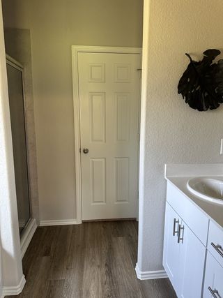 Model Home A modern bathroom with a sleek white vanity, wood-look flooring, and a shower enclosure for a stylish touch.