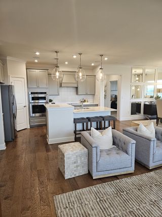 A modern open-plan kitchen with grey cabinetry, stylish pendant lights, and plush seating for a cozy, elegant living space.
