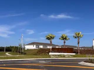A contemporary community entrance with palm trees at Westview: Overlook Townhomes by Lennar in Kissimmee, FL.
